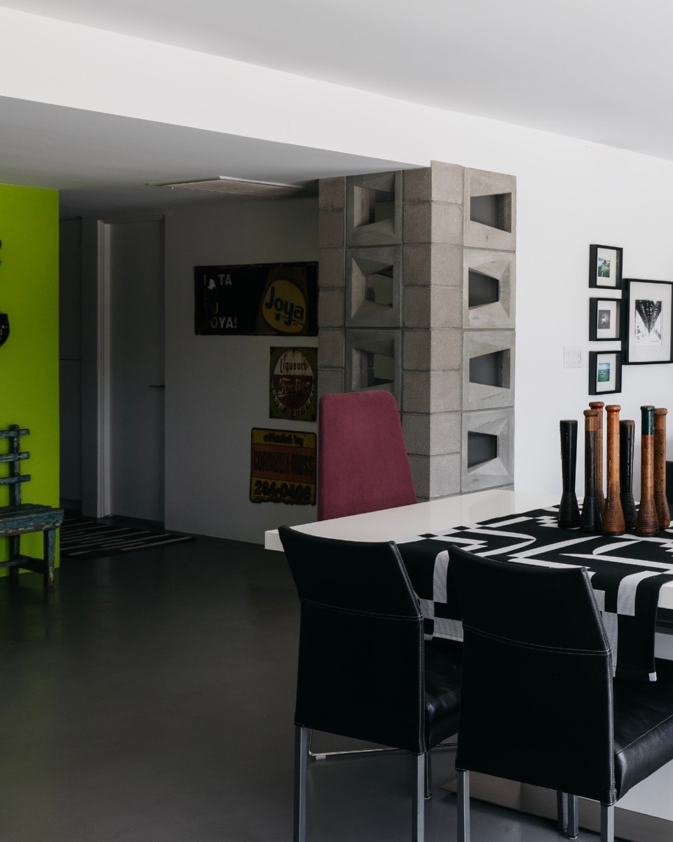 Graphic open-plan dining room with dark finishes and bright art